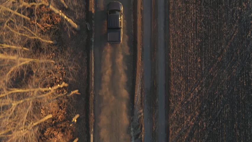 Aerial shot of pickup truck driving through rural path near ploughed field. Flying over black car moving along road near plowed meadow at autumn. Off road vehicle moving on route near farmland Royalty-Free Stock Footage #1101400683