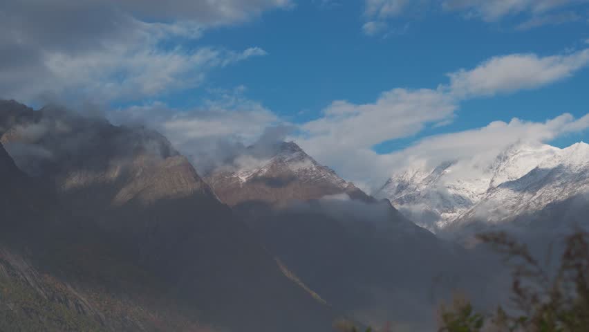 4K shot of clouds moving under the snow covered mountain peaks during the winter storm at Tinnan valley in Lahaul Spiti, Himachal Pradesh, India. Clouds below snowy himalayan mountains in India. 