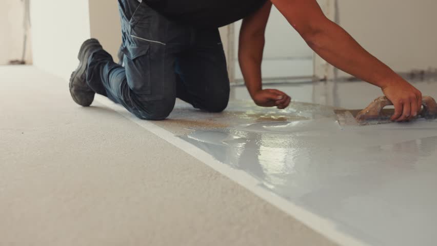 worker mixes the two-part epoxy resin and hardener together according to manufacturer instructions, and applies it to the surface using a squeegee.  Royalty-Free Stock Footage #1101401999