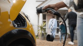 Close up of woman plugging electric charger into car - Powered by Shutterstock - Get 15% off with code: PIKWIZARD15