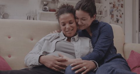 Lesbian Couple Enjoying Pregnancy, Embracing on Sofa 庫存影片