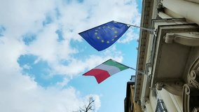 Italy and Euro. National country flag on blue sky background. Flying fabric symbol. Tourism or travel summer day. international patriotic emblem. Nobody. Horizontal video