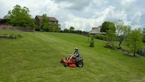 Clip of a man on a riding lawn mower in the backyard