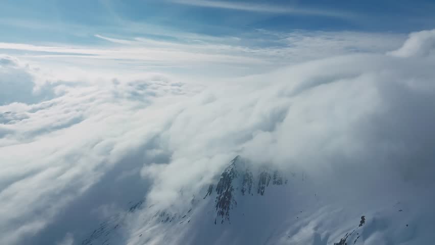 Alpine landscape with peaks covered by snow and clouds. Magical clouds covering peaks of the mountains at the famous St. Anton am Arlberg ski resort.
