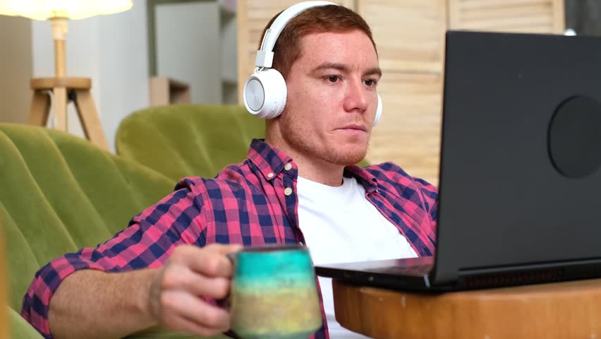 Coffee breaks help revitalize tired workers and maintain productivity, red-haired, freckled man drinking coffee while working on his laptop. significance of taking breaks to sustain productivity. Royalty-Free Stock Footage #1101408203