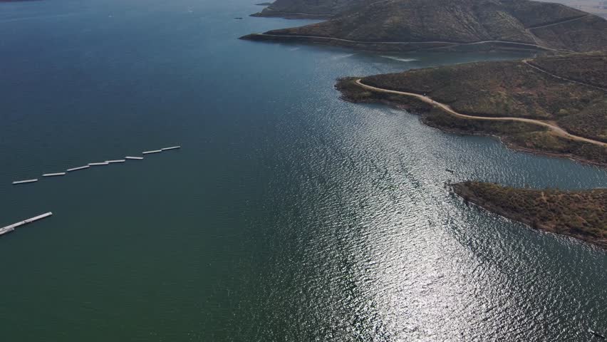 stunning aerial footage of the vast blue waters of the lake surrounded by majestic mountain ranges covered with lush green plants with blue sky in summer at Diamond Valley Lake in Hemet California USA