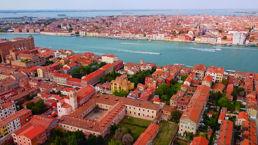 Aerial view of the city on the water and rooftops, the bell tower of the basilica and the unique canals with boats, crossing Venice and Italy. Gondolas with tourists. Carnival and Film Festival. Masks