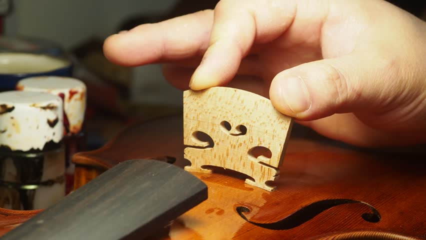 Artisan placing the violin, viola, or cello bridge for playability, tone, and structural integrity | Shutterstock HD Video #1101413931