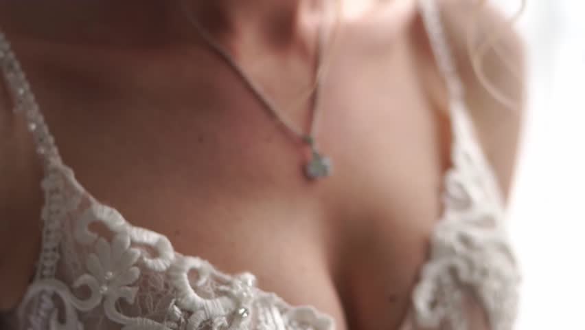 Pendant with a diamond around the neck of a bride in a white dress. Cropped