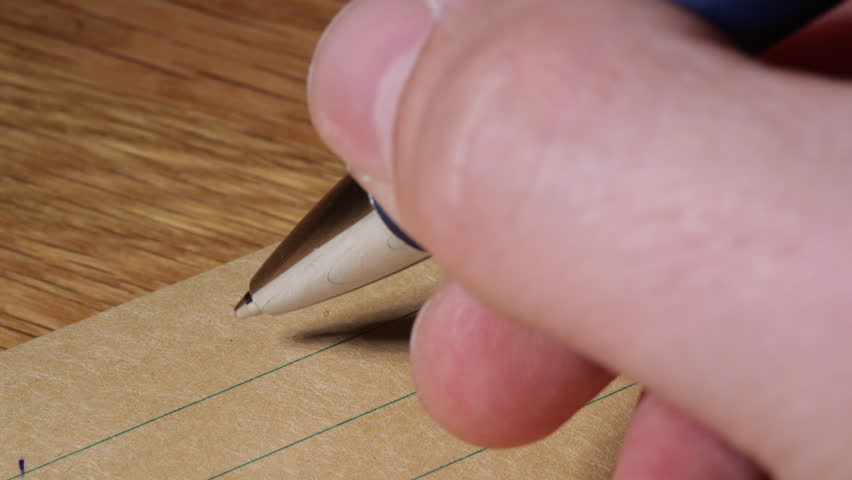 Person writing self help letter for goal setting idea on brown lined paper