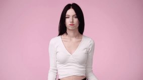 4k video of one girl pointing at left over pink background.