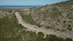Three cyclists conquer Vall d'Ebo pass in Spain.Cyclists training on bicycles in mountains.Pedaling to the top.Cycling through the mountains.Three athletes  training on Vall de ebo pass.Drone video 4k