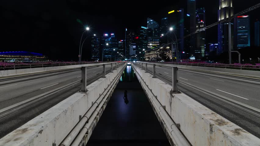 timelapse traffic on the highway street road on bridge over singapore marina bay with background of city metropolis highrise skyscraper building skyline at night time in Singapore.
