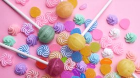 Various candy lollipops and sweets.  Slow motion. Video on pink background