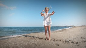 Ukrainian girl in shirt with floral wreath with multi-colored ribbons dances on coast near Black sea