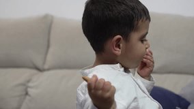 Video of an autistic young man leaning on his sofa playing with a piece of bread to eat it.