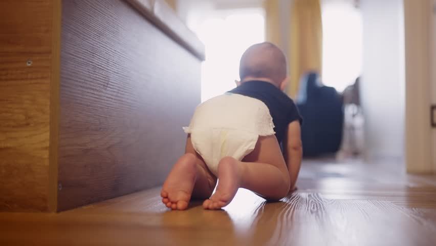 baby learns to crawl on floor at home. happy family kindergarten kids concept. First steps, baby crawling view from the back. baby learns to crawl to explore the world dream around him Royalty-Free Stock Footage #1101438395