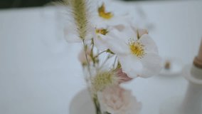 Close-up small tender bouquet with pastel wild flowers and spikelets on wedding table at small cozy wedding party, handheld shot, slow motion. - Powered by Shutterstock - Get 15% off with code: PIKWIZARD15