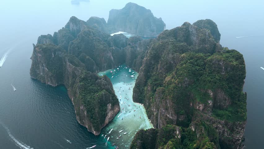 Top view of the whole island of Ko Phi Phi Lee with iconic Maya Bay and Pileh Lagoon surrounded by limestone cliffs on Phi Phi islands in Thailand. Thailand's most popular tourist attraction. | Shutterstock HD Video #1101450463