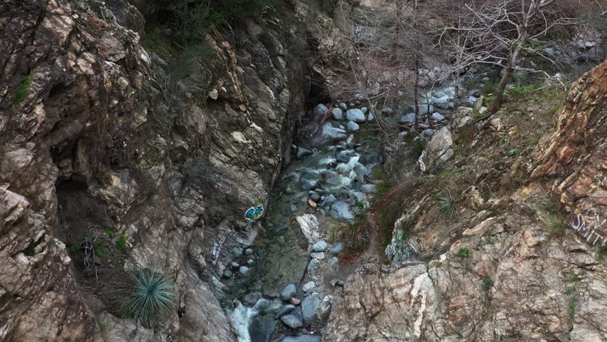 Hikers gathered around Eaton Canyon Falls after a long hike in Angeles National Forest, California. Aerial dolly back tilt.