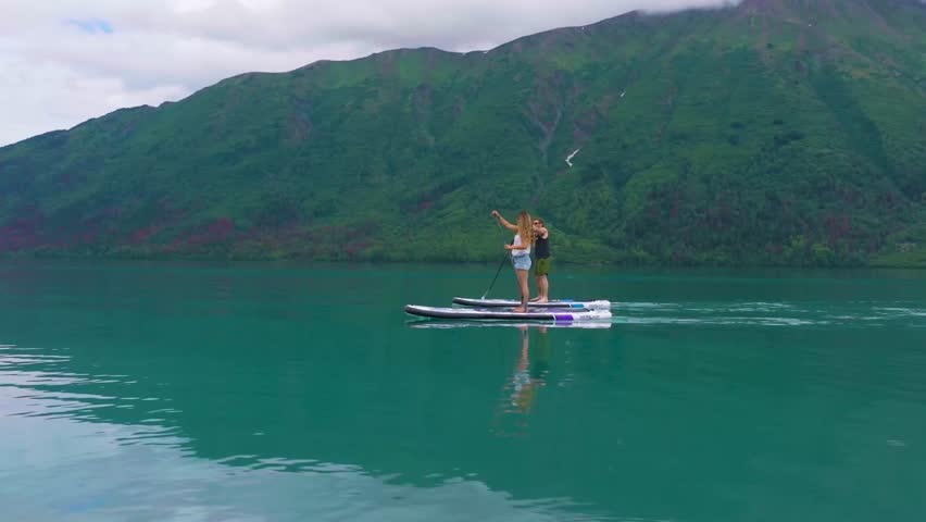 A couple paddle boarding on Kenai Lake in Alaska.