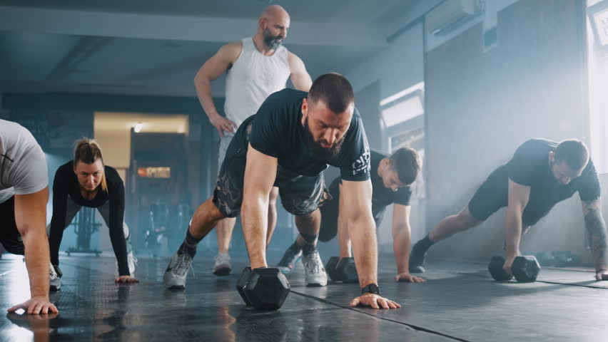 Fitness group people doing Alternating Renegade Row exercises using dumbbells while exercising in the gym Royalty-Free Stock Footage #1101456821