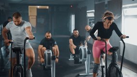 Attractive woman bodybuilder and man doing exercise on stationary bike an two men work out together on rowing gym machines slow. Group training - Powered by Shutterstock - Get 15% off with code: PIKWIZARD15