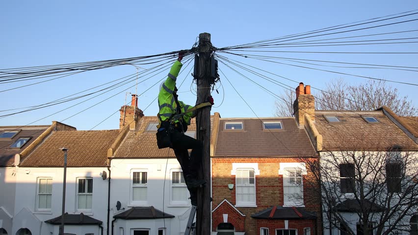 Telecommunication engineer performing maintenance on cables at the top of a telephone pole. Royalty-Free Stock Footage #1101458189