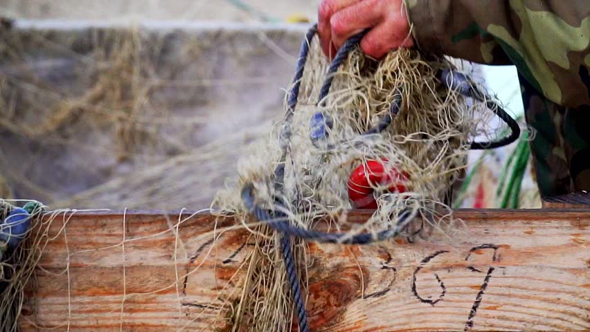 Slow motion shot of a fisherman sorting out his hand-casting nets