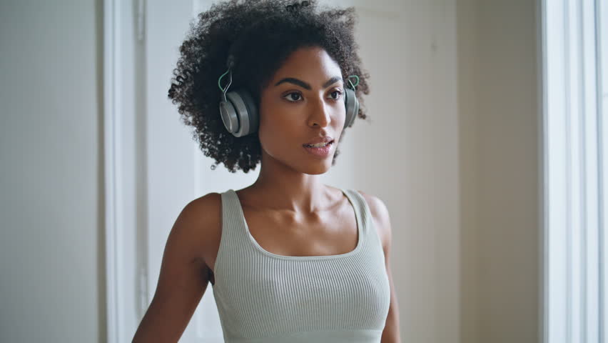 Yoga woman smiling camera at home portrait. Serene headphones sportswoman stretching alone training at morning closeup. African sportive lady enjoying music having domestic routine. Healthy practice Royalty-Free Stock Footage #1101460787