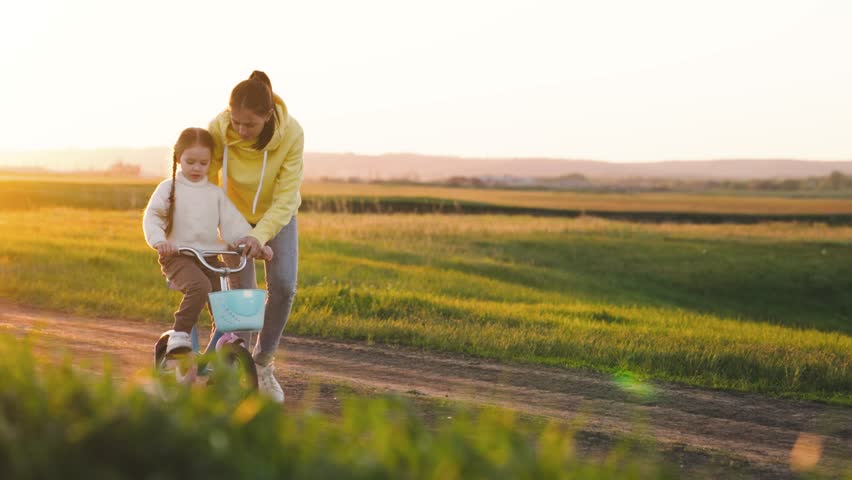 mother teaches child ride two-wheeled bicycle sunset. fun weekend by bike. child's dream kid. child drive bicycle. mom rides girl child daughter bikerays sunset. happy family concept. teamwork. Royalty-Free Stock Footage #1101463415