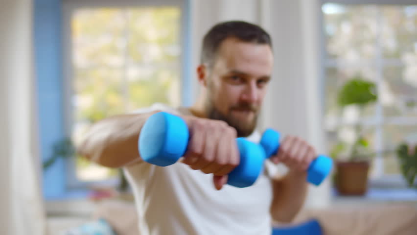 Boxer practices punches with dumbbells in his hands at home. Man exercises boxing with sports equipment. Professional sportsman training at home. Guy use dumbbells working out. Realtime | Shutterstock HD Video #1101470715
