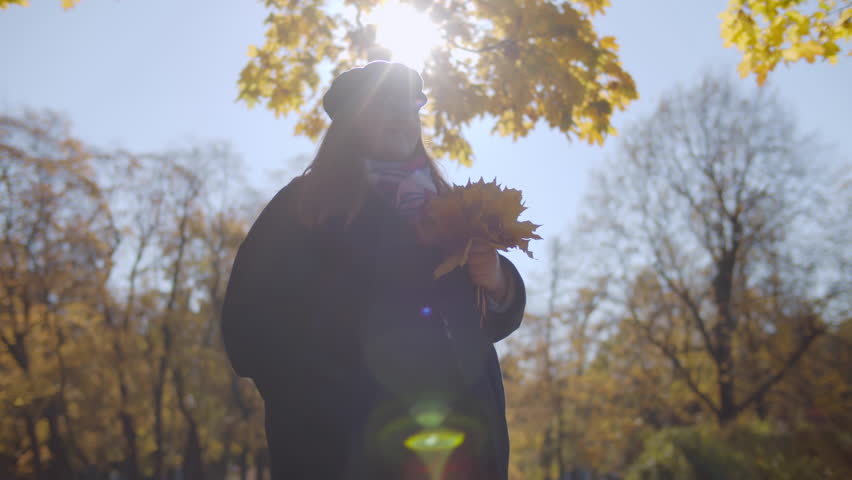 Happy body positive woman hold bouquet of fallen yellow leaves in the autumn park. Low angle view of plus size smiling female with maple leaves in autumn forest. Happy female outdoors. Realtime | Shutterstock HD Video #1101470717