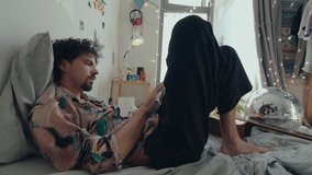 Young man chilling on bed, turning pages and reading a book, spending leisure time at home in a room decorated with trendy diy things. Side view medium shot - Powered by Shutterstock - Get 15% off with code: PIKWIZARD15