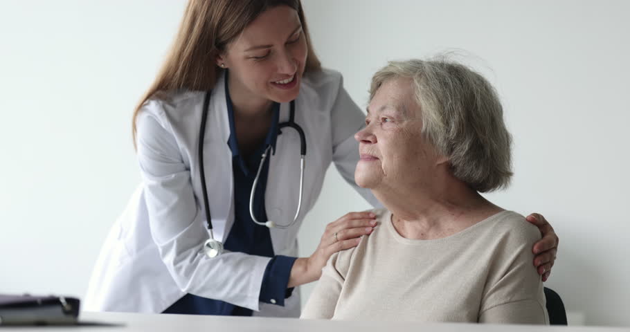 Positive caring physician doctor giving medical support, healthcare help, consultation to old patient, touching shoulders, hugging elderly 80s woman, smiling, laughing, talking Royalty-Free Stock Footage #1101476227