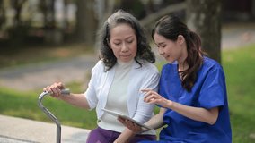 Delighted doctor in uniform pointing on digital tablet and showing medical reports to elderly woman at outdoor nursing home