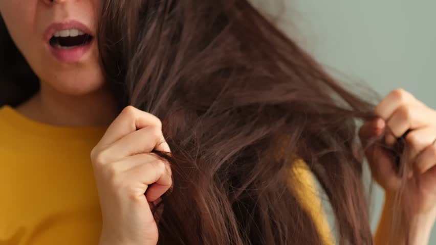 troubled brunette woman struggling with dry and knotted hair, hair mishap and the search for effective solutions to keep hair looking and feeling its best. Bad Hair Day. Royalty-Free Stock Footage #1101488191