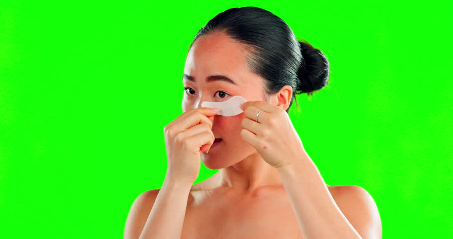 Face, skincare and Asian woman with eye patches on green screen in studio isolated on a background mockup. Dermatology, cosmetics and happy female model apply facial mask for healthy skin treatment. | Shutterstock HD Video #1101488579