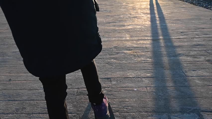A girl rides a scooter along the embankment on a spring day at sunset. The Black Sea coast with beautiful hotels. Georgia, Batumi. 