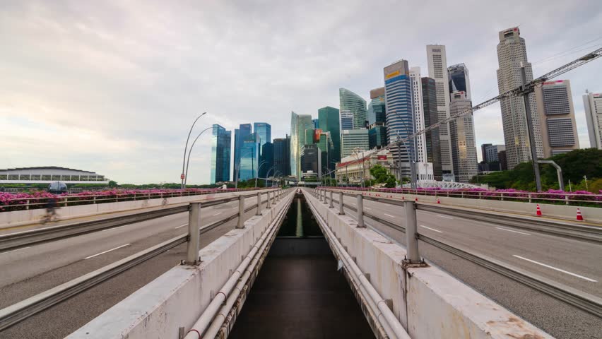 timelapse traffic on the highway street road on bridge over singapore marina bay with background of city metropolis highrise skyscraper building skyline at sunset time in Singapore.