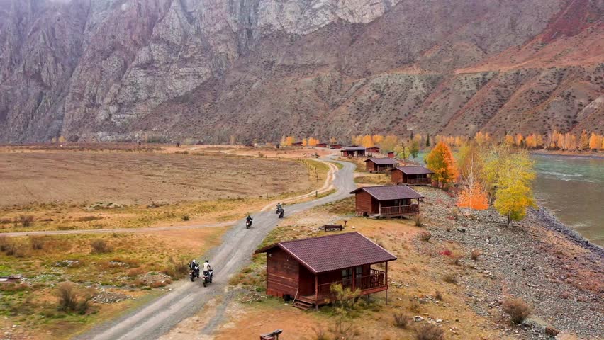 Motorcyclists ride near a mountain river in Altai. High quality 4k footage. Flying a drone over the beautiful landscapes of the Altai Republic Royalty-Free Stock Footage #1101496363