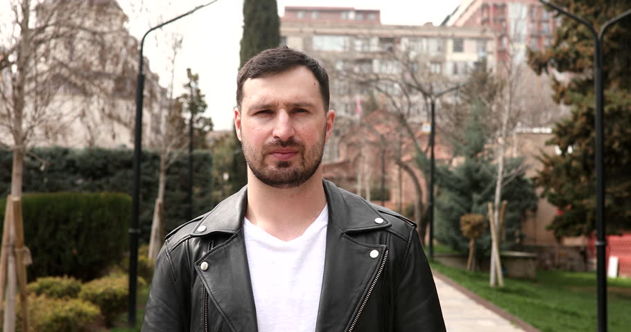 Man greeting with namaste gesture on street.