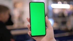 Handheld Camera: Point of View of Woman in the mall Using Phone With Green Mock-up Screen Chroma Key Surfing Internet Watching Content Videos Blogs Tapping on Center Screen 4K