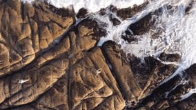 Fishermen fishing on rocky cliff of Punta del DiabloPunta del Diablo, Uruguay. Aerial top-down orbiting directly above