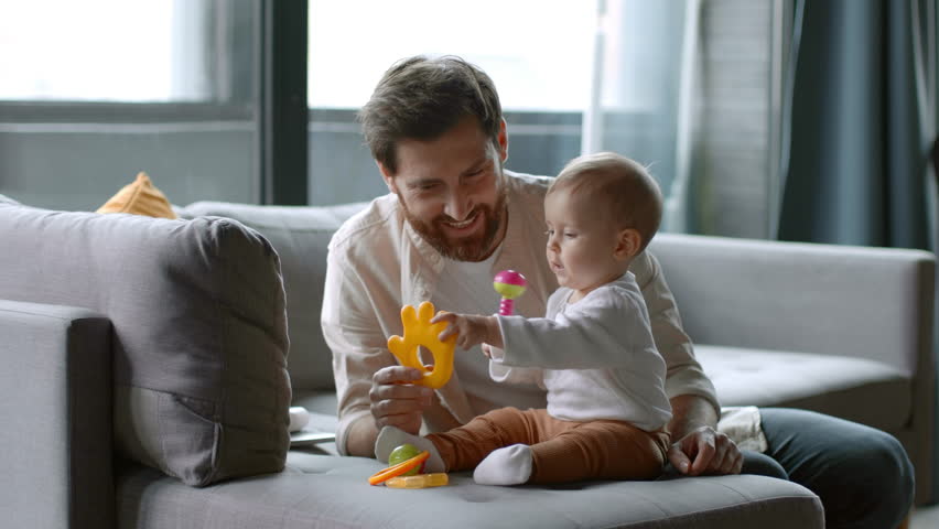 Playtime at home. Happy loving daddy playing with his cute baby daughter, having fun with rattles and developing toys, enjoying paternity leave, free space Royalty-Free Stock Footage #1101507935