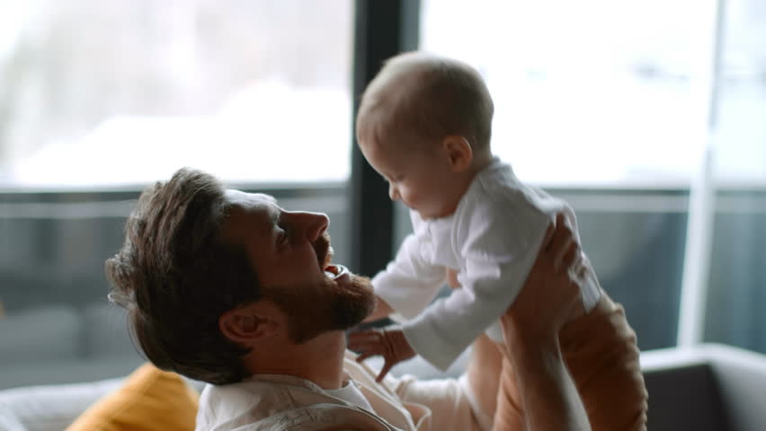 Happiness of parenthood. Young loving man playing with his adorable baby daughter, lifting kid up and rubbing noses, spending weekend at home, free space Royalty-Free Stock Footage #1101507957