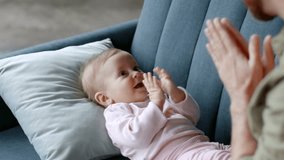 Infant entertainment. Cute little baby girl lying on sofa and clapping hands, loving unrecognizable man playing with his adorable daughter, tracking shot, slow motion, free space - Powered by Shutterstock - Get 15% off with code: PIKWIZARD15