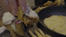 This close up video shows a hand shaking powdered sugar off of Korean fried chicken in slow motion.