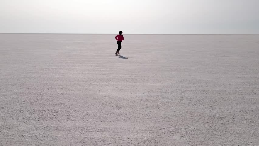 Aerial shot of an Asian woman jogging across the Bonneville Salt Flats flats in Utah