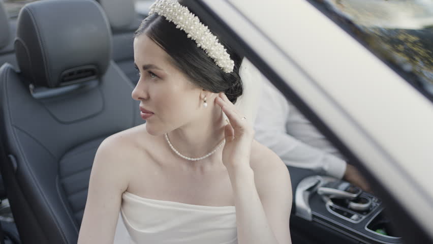 Bride and groom in wedding clothes sitting in cabriolet car. Action. Man and woman in luxury car.